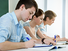 Students take exam in row with pens in hand