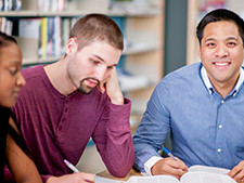 Students sits working on assignment with hand resting on face looking sad