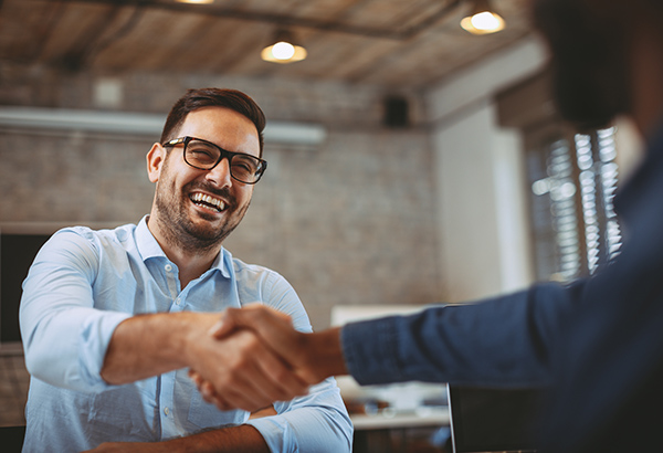 Man laughs while shaking another person's hand