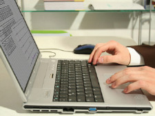 Person's hands type at computer keyboard