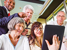 A group of people look over computer pointing and smiling