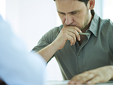 Man looks down with hands by mouth looking distressed