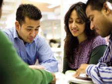 Students of different ethnicities sit down at table and collaborate