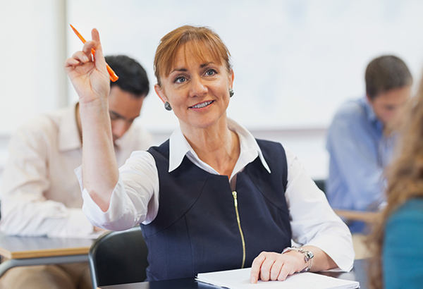 Middle-aged woman raises hand in class with questions