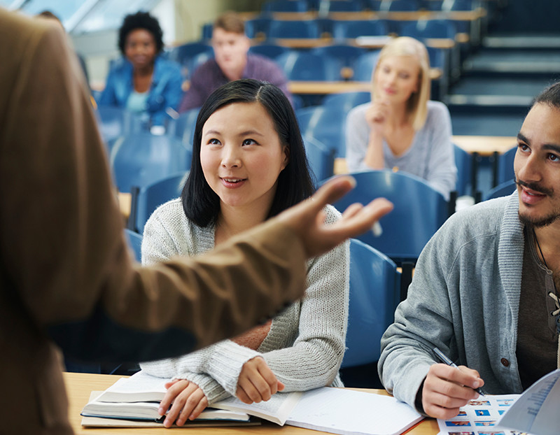 Students sit at desks looking up at mini-lectures