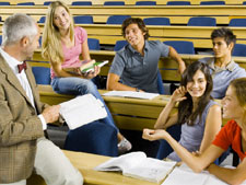 Group of students sit in large lecture hall discussing with teacher