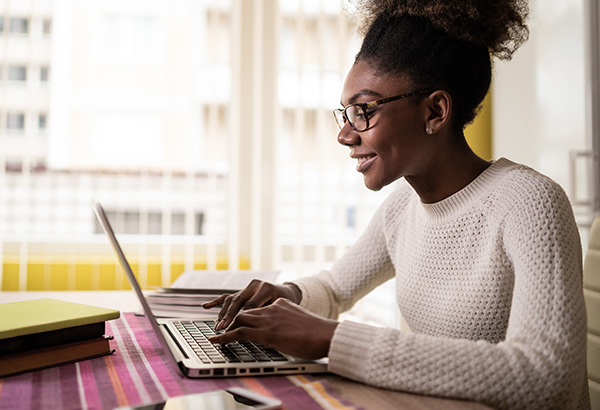 Person types on keyboard while smiling at computer