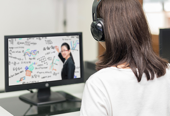 Person with headphones listens to instructor teach on computer