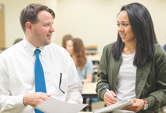 Two people look at each other with papers in hand