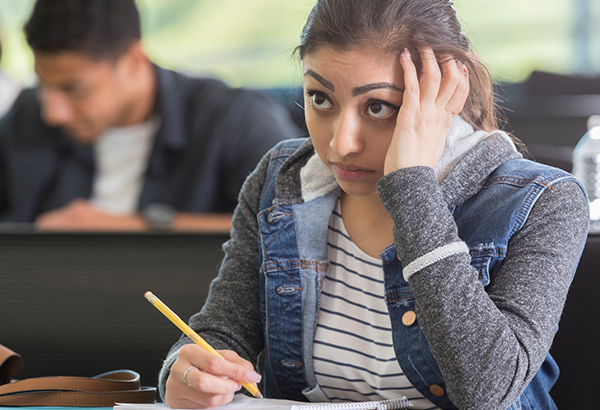 Student hides face in hand while taking notes for a trauma sensitive classroom