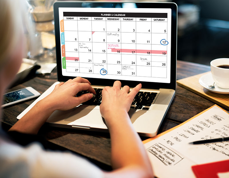 Person types on computer displaying intricate and planned calendar full of events