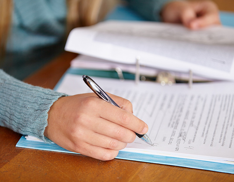 Person holds pen and writes notes on binder paper