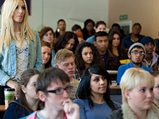 Student stands up among others sitting in the classroom showing a Transformative Learning Experience