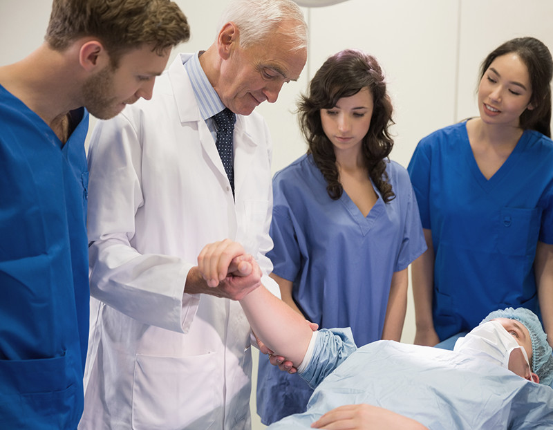 Doctor checks patient's pulse while students observe