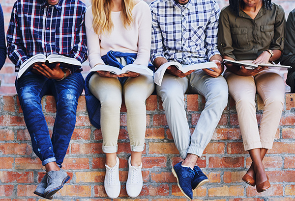 Students read course readings books along wall