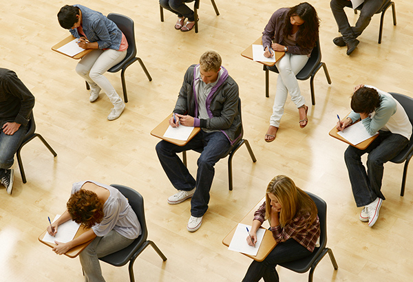 students-working-in-room-taking-exam-at-desks