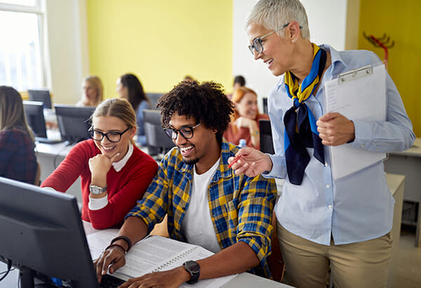 teacher-guiding-students-working-at-computer