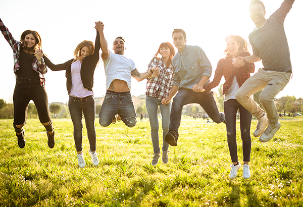 group-of-students-jumping-outside-grass-sunshine