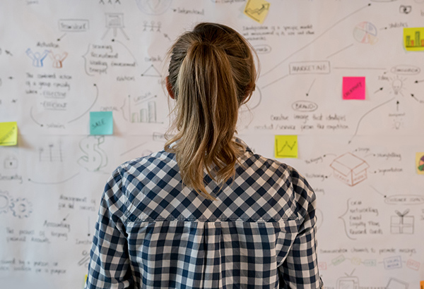 woman-looking-at-idea-board-notes-post-its