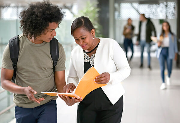 student-walking-with-teacher-comparing-notes