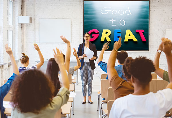 teacher-in-front-of-class-of-engaged-students-all-raising-their-hands