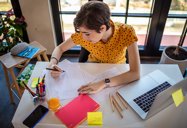 woman-actively-working-at-desk-making-notes-near-computer