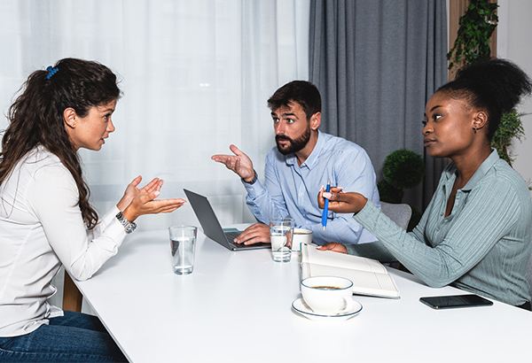 three-people-talking-at-table-discussing-mediating-and-resolving-conflict