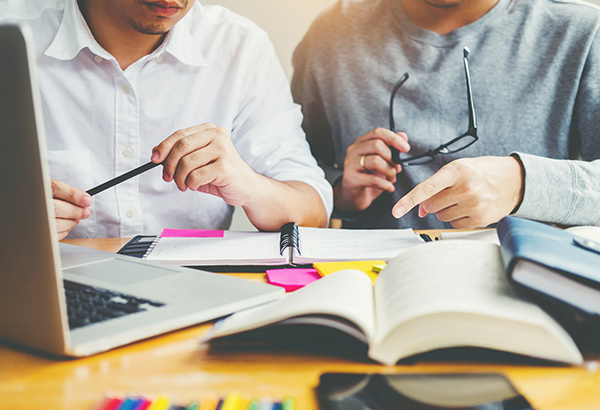 student-and-teacher-at-desk-discussing-assignments