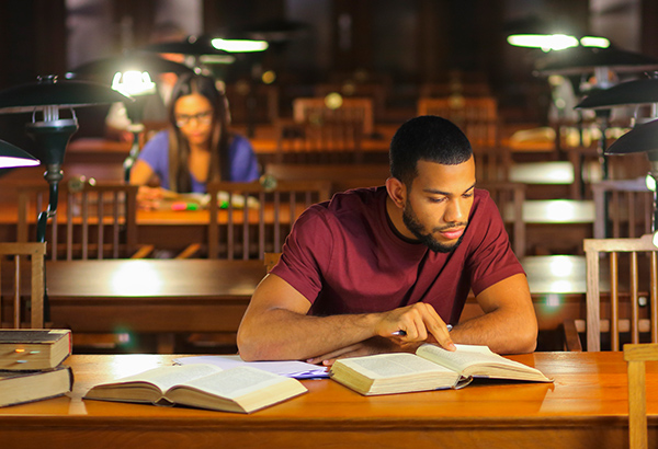 students-in-library-studying-with-open-books-at-desk