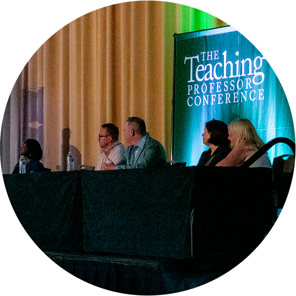 panel of educators sitting at a table in the front of a large audience